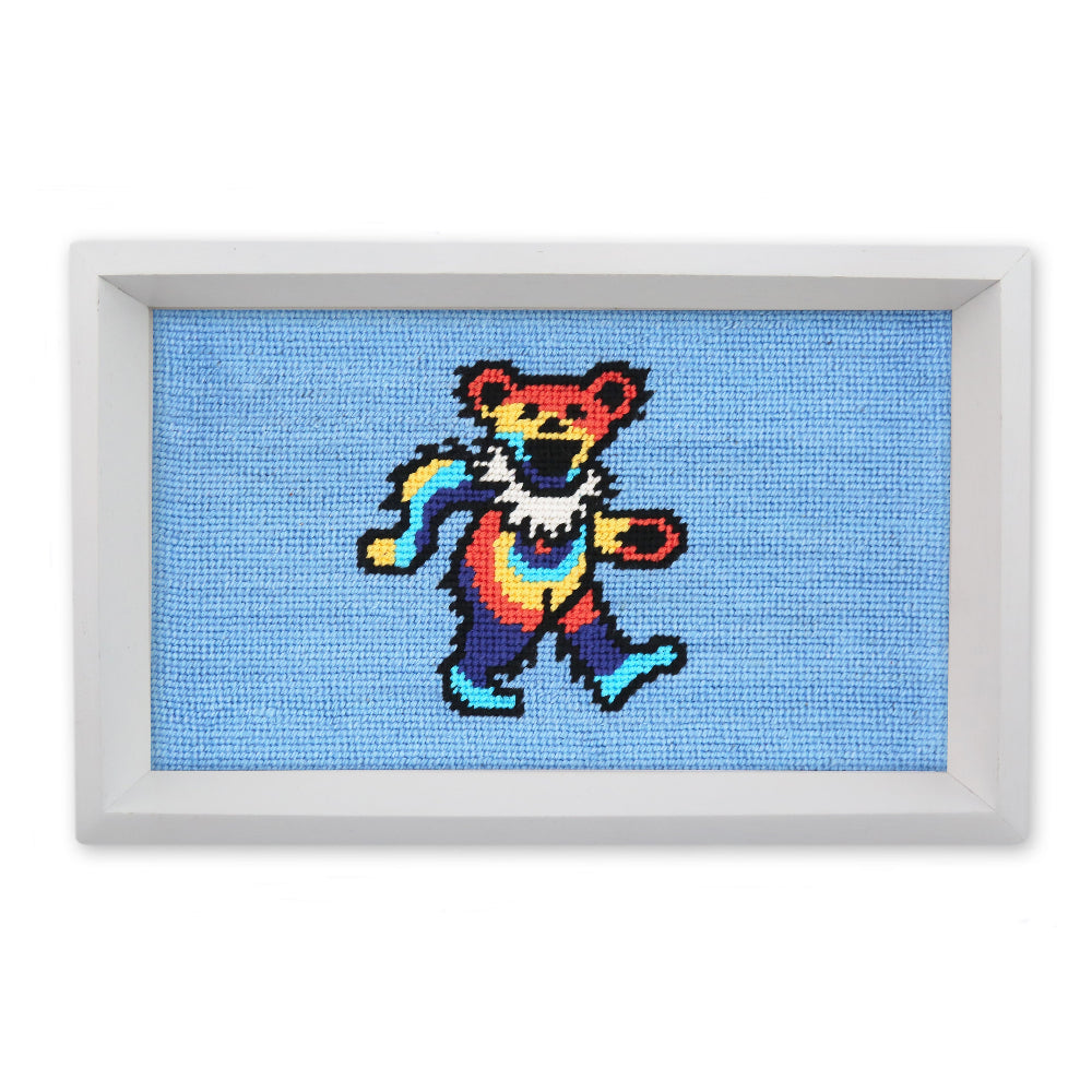 Framed cross-stitched artwork of a colorful bear on a blue background
