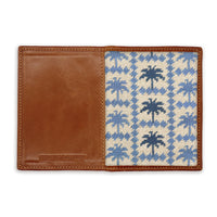 Wallet with brown leather section and blue palm tree patterned interior on a white background