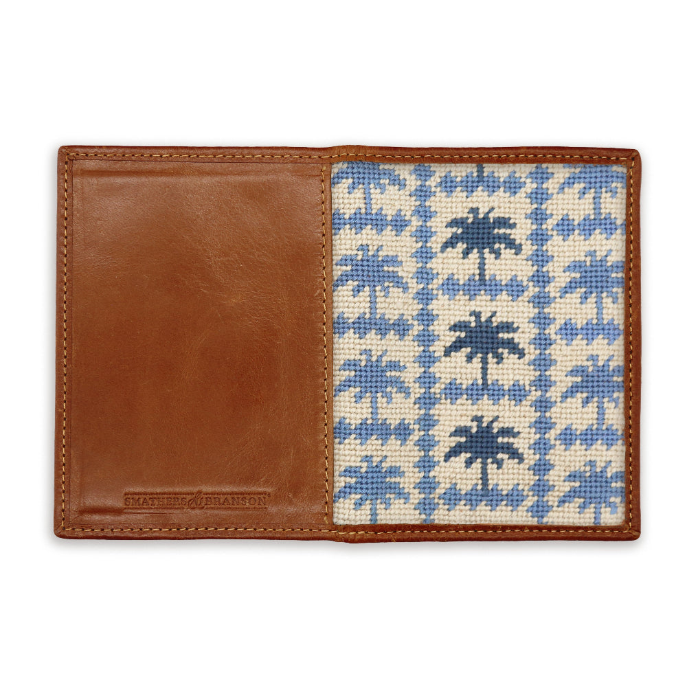 Wallet with brown leather section and blue palm tree patterned interior on a white background