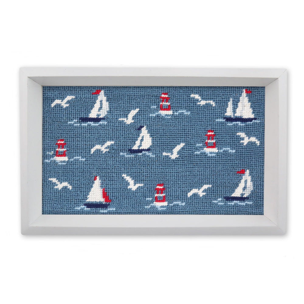 Framed needlepoint with sailboats, lighthouses, and seagulls on a blue background.