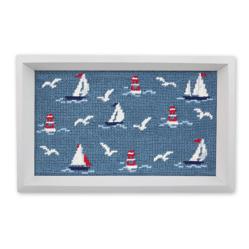 Framed needlepoint with sailboats, lighthouses, and seagulls on a blue background.
