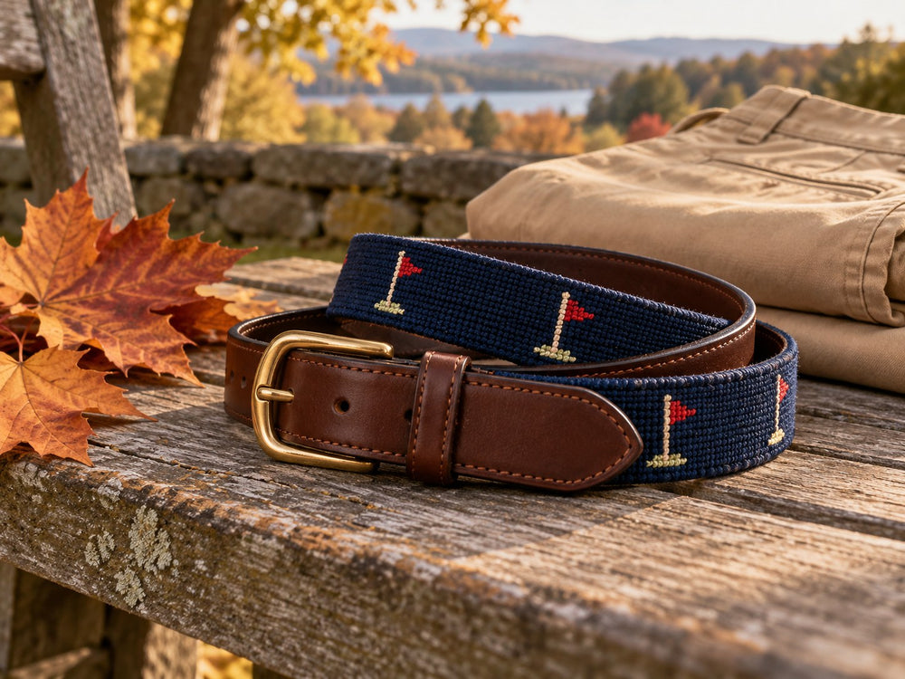 Navy needlepoint golf motif belt with brown leather and a brass buckle